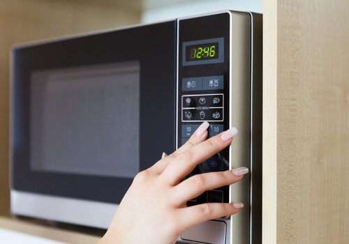 電子レンジを操作する女性の手