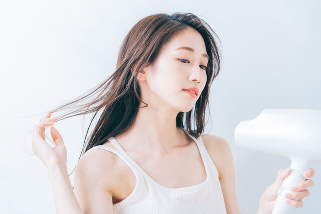髪をドライヤーで乾かす女性