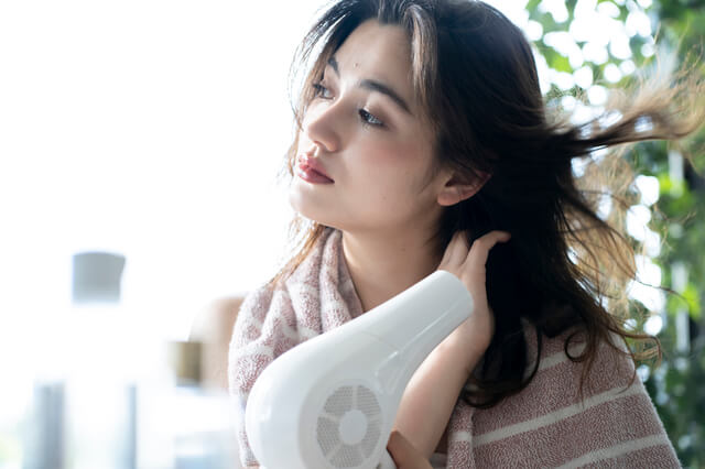 ドライヤーで髪を乾かす女性