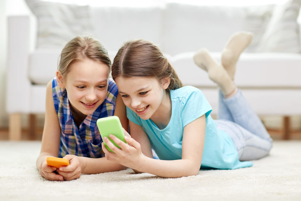 2人の女の子が横になってスマホを見ている
