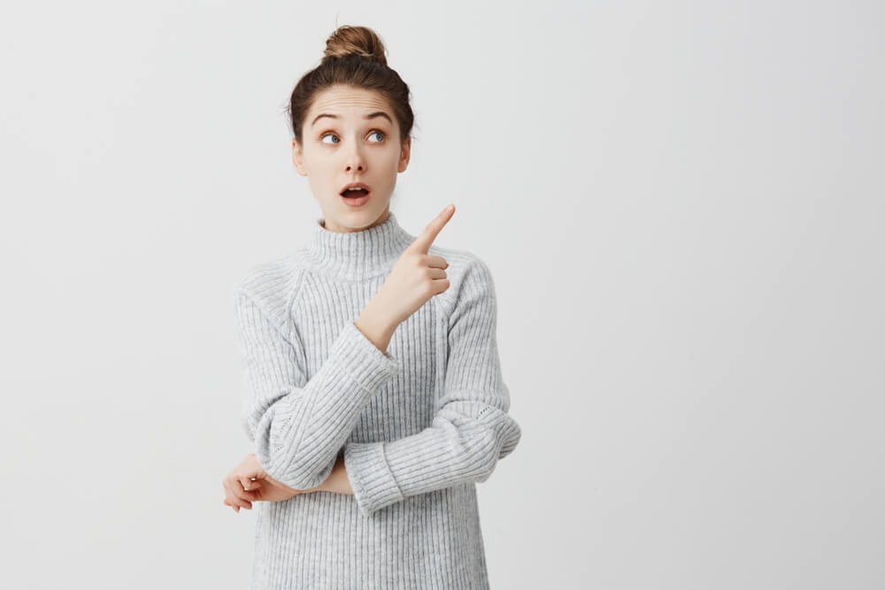 人差し指で横を見させる女性